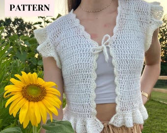 May include: White crochet top with a tie front and ruffled sleeves. The top is worn over a white tank top and brown skirt.