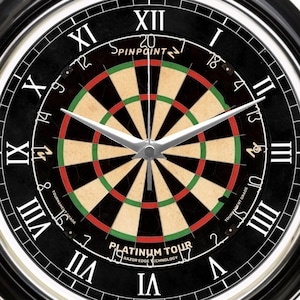May include: Black wall clock with a dartboard design. The clock face features a dartboard center with red, green, and tan colors. The clock has Roman numerals and the text "PLATINUM TOUR" and "SPINPOINT".