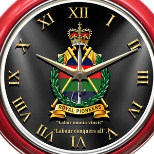 May include: A circular wall clock with a red surround and a black face. The clock displays gold Roman numerals, gold hands, and a crest with the words "Royal Pioneers" and the motto "Labor omnia vincit".