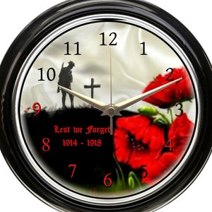 May include: A black and silver wall clock with a red poppy design. The clock face has black Roman numeral hour markers and red Arabic numeral minute markers. The clock face also features a silhouette of a soldier standing in front of a cross with the text "Lest we Forget 1914-1918".