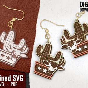 May include: A pair of gold-colored earrings featuring a cactus and a cow skull design. The cactus is brown and white, and the cow skull is white. The earrings are in a pot with star details. The text "DIGITAL DOWNLOAD" is visible.