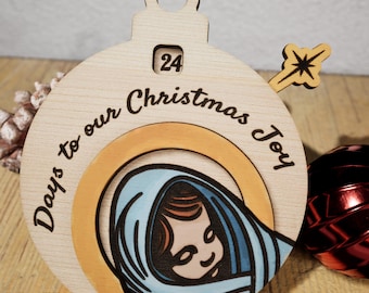 May include: A wooden Christmas ornament with a countdown to Christmas Joy. The ornament features a depiction of Mary holding baby Jesus, with a star on top. The ornament is numbered 24, indicating the 24th day of advent.
