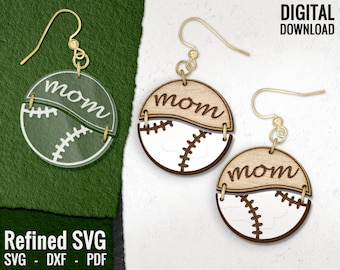 May include: A pair of wooden earrings with a baseball design. The earrings are cut out in the shape of a baseball with the word "mom" written on the top half of the baseball. The bottom half of the baseball is white with black stitching.