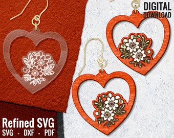 Könnte beinhalten: Ein Paar rote herzförmige Ohrringe mit einem weißen Blumendesign im Herzen. Die Ohrringe sind aus Holz und haben einen goldfarbenen Haken.