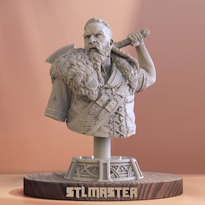 May include: A 3D printed bust of a Viking warrior with a beard and axe, wearing a fur-lined cloak and leather armor. The bust is mounted on a wooden base with the word "STLMASTER" engraved on it.