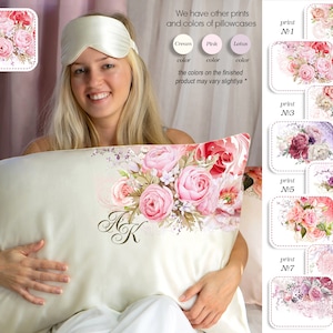 May include: A white silk pillowcase with a floral print featuring pink roses and green leaves. The pillowcase has the initials "A K" embroidered in a cursive font. The image also shows a selection of other floral prints for pillowcases, including cream, pink, and lotus colors.