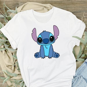 May include: White t-shirt with a blue cartoon Stitch character sitting on the front of the shirt.