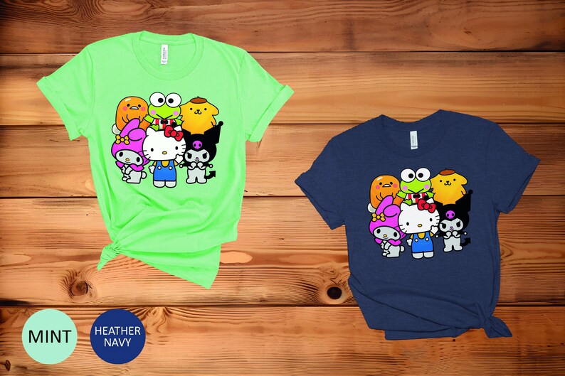 May include: A green t-shirt featuring a graphic of Hello Kitty and her friends, including My Melody, Keroppi, and Badtz-Maru. The graphic is in a cartoon style and shows the characters in various poses.