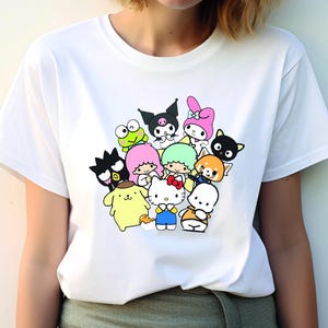 May include: White t-shirt with a colorful graphic print of various cartoon characters, including Hello Kitty, My Melody, and Keroppi.