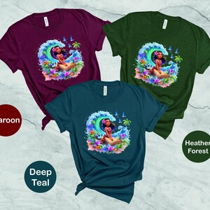 Peut inclure: Trois t-shirts avec une image de dessin anim&eacute; d'une femme sur une vague. Les t-shirts sont bordeaux, bleu sarcelle fonc&eacute; et for&ecirc;t chin&eacute;e.