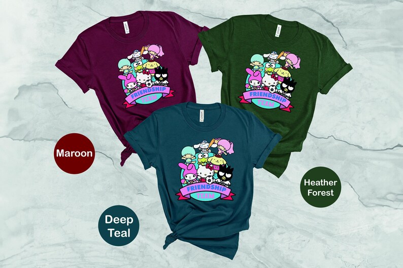 May include: Three t-shirts in maroon, deep teal, and heather forest colors. Each shirt features a graphic print of cartoon characters with the text "Friendship Goals".