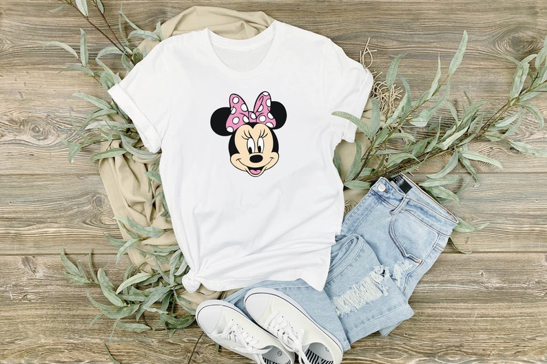 May include: White t-shirt with a cartoon image of Minnie Mouse wearing a pink bow with white polka dots.