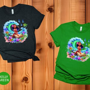Peut inclure: Deux t-shirts avec un motif color&eacute; d'un personnage de dessin anim&eacute; sur une vague. Le personnage a de longs cheveux bruns et porte un haut rouge. Les t-shirts sont disponibles en gris fonc&eacute; chin&eacute; et vert kelly.