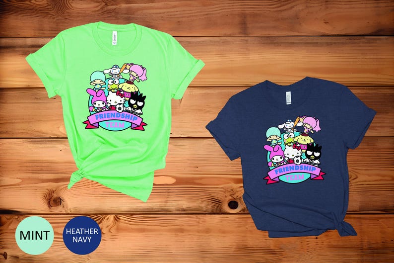 May include: Two t-shirts with a graphic print of cartoon characters. The green t-shirt has the text "Friendship Team" in a purple banner. The blue t-shirt has the same graphic and text.