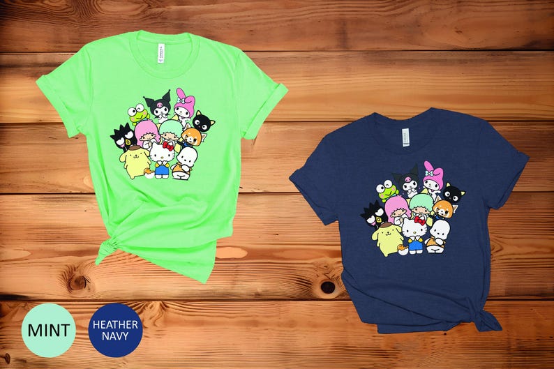 May include: Two t-shirts with a graphic print of a group of cartoon characters. The t-shirt on the left is a bright green color and the t-shirt on the right is a dark blue color.