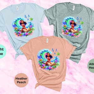 Peut inclure: Trois t-shirts avec un motif color&eacute; d'un personnage de dessin anim&eacute; sur une vague. Les t-shirts sont en bleu clair, p&ecirc;che chin&eacute; et gris chin&eacute;.