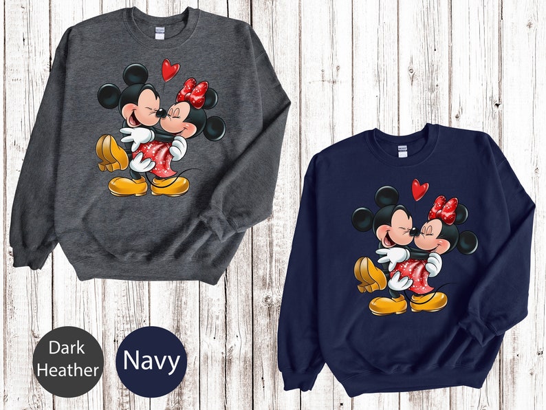 May include: A dark heather grey and a navy blue sweatshirt with a graphic of Mickey Mouse and Minnie Mouse kissing. The graphic is in red, yellow, and black.