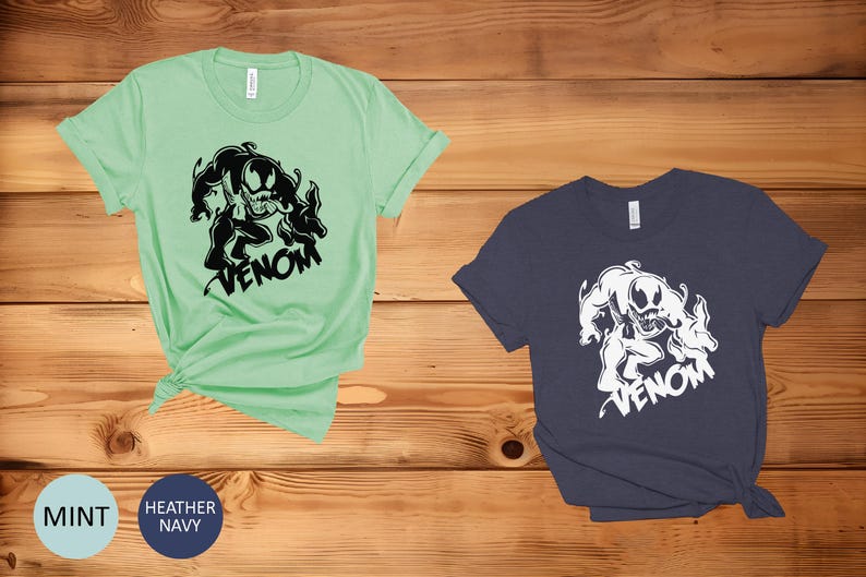 May include: Two t-shirts with a black and white graphic of Venom, a Marvel Comics character. The t-shirts are available in mint green and heather navy.