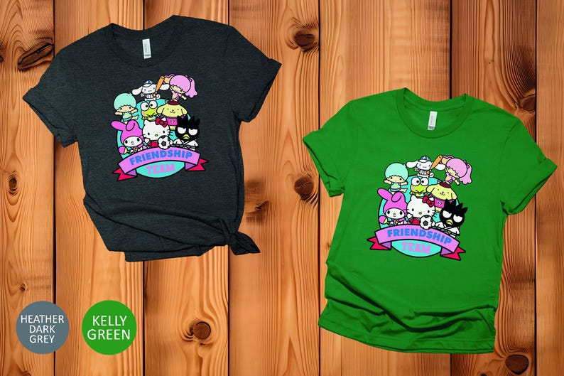 May include: Two t-shirts with a graphic print of cartoon characters. The t-shirt on the left is heather dark grey and the t-shirt on the right is kelly green. Both t-shirts feature the text "Friendship Team".