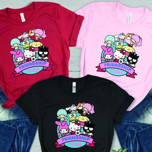 May include: Three t-shirts in red, pink, and black with a graphic of cartoon characters and the text "Friendship Team".