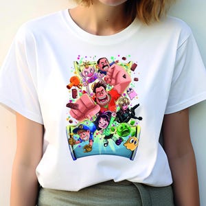 May include: White t-shirt with a colorful graphic print of characters from the movie Wreck-It Ralph. The characters are in a playful pose, surrounded by colorful confetti and candy.