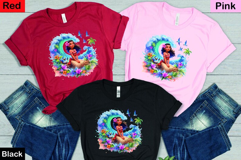 Peut inclure: Trois t-shirts avec une image de dessin anim&eacute; d'une fille aux longs cheveux noirs et une tenue bleue et verte chevauchant une vague. Les t-shirts sont rouge, rose et noir.