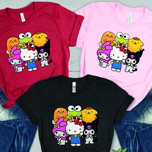 May include: Three t-shirts featuring a graphic print of Hello Kitty and her friends. The t-shirts are available in red, pink, and black.