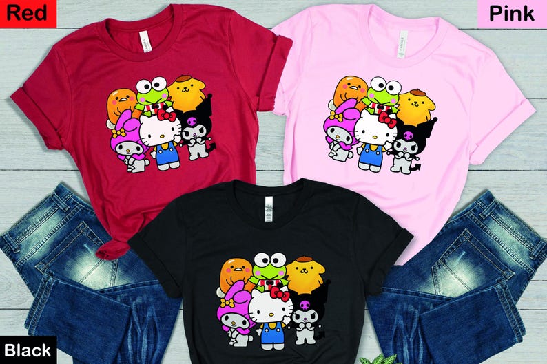 May include: Three t-shirts featuring a graphic print of Hello Kitty and her friends. The t-shirts are available in red, pink, and black.
