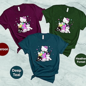 Pu&ograve; includere: Tre t-shirt con una stampa grafica di Hello Kitty e i suoi amici. Le t-shirt sono di colore granata, blu petrolio scuro e bosco melange.
