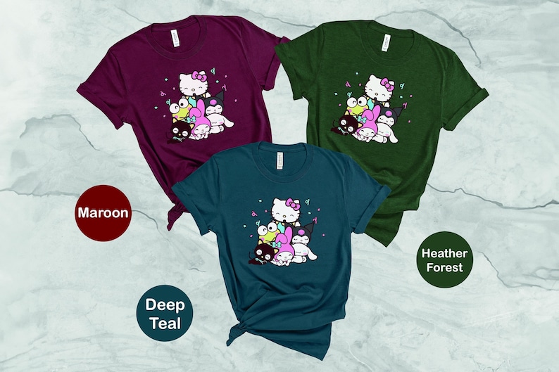 Pu&ograve; includere: Tre t-shirt con una stampa grafica di Hello Kitty e i suoi amici. Le t-shirt sono di colore granata, blu petrolio scuro e bosco melange.