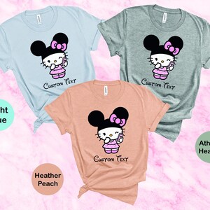 Pu&ograve; includere: Tre magliette a maniche corte in azzurro, grigio atletico e pesca melange. Ogni maglietta presenta un personaggio dei cartoni animati con una testa nera a forma di orecchio di topo, un fiocco rosa e un vestito rosa, che tiene in mano un telefono. Il testo "Custom Text" &egrave; sotto.