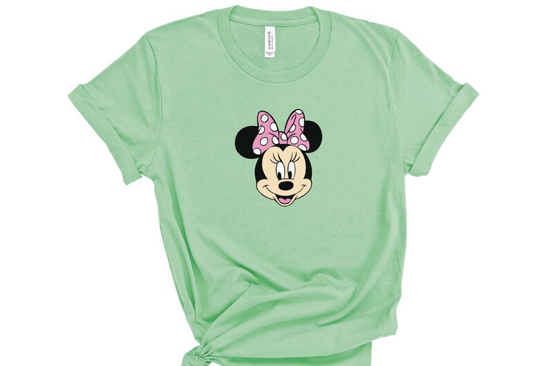 May include: A light green t-shirt with a cartoon image of Minnie Mouse wearing a pink polka dot bow.