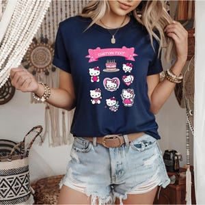 May include: Navy blue t-shirt featuring a collection of Hello Kitty graphics. The design includes various poses of the character, a birthday cake, and a banner with the text "CUSTOM TEXT". The shirt has short sleeves and a classic crew neck.