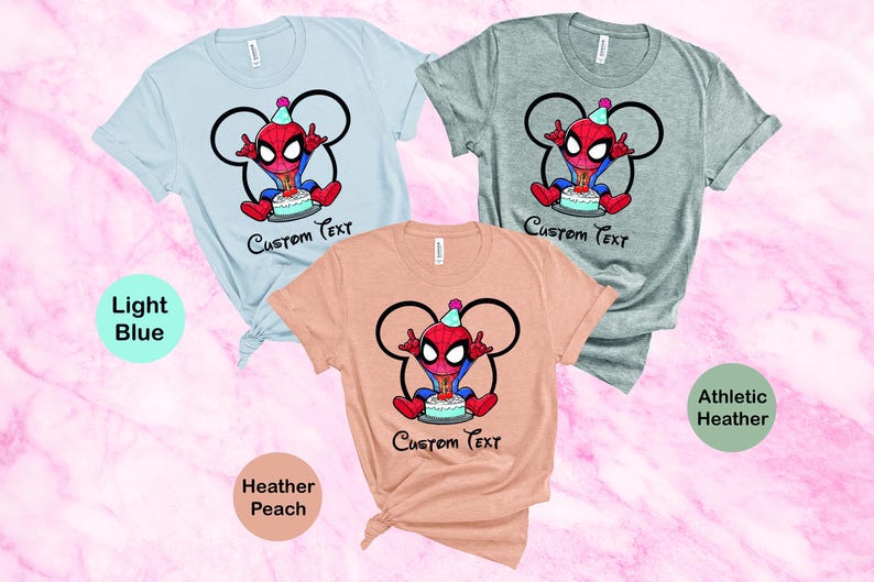 May include: Three t-shirts in light blue, athletic heather, and heather peach. Each shirt features a cartoon Spider-Man character with a birthday cake and the text "Custom Text". The design is framed by a Mickey Mouse-style outline.