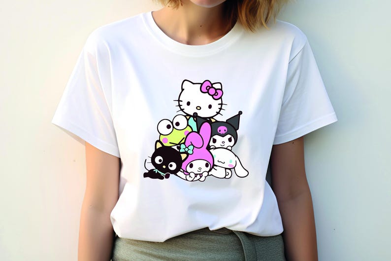K&ouml;nnte beinhalten: Wei&szlig;es T-Shirt mit einem Grafikdruck von Hello Kitty und ihren Freunden. Die Figuren sind &uuml;bereinander gestapelt, mit Hello Kitty oben. Die Figuren sind alle in Schwarzwei&szlig;, au&szlig;er Hello Kittys rosa Schleife.