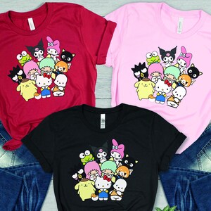 May include: Three t-shirts with a graphic print of various cartoon characters, including Hello Kitty, My Melody, and Keroppi. The t-shirts are available in red, pink, and black.