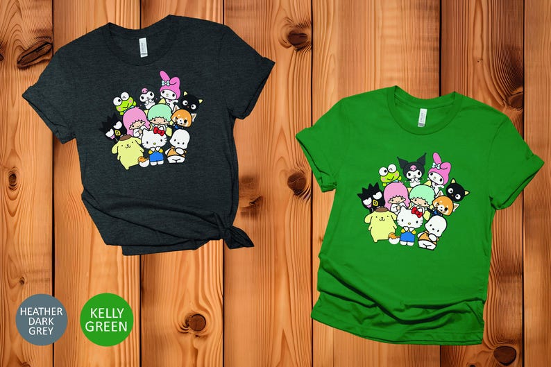 May include: Two t-shirts with a graphic print of a group of cartoon characters. The shirt on the left is heather dark grey and the shirt on the right is kelly green.