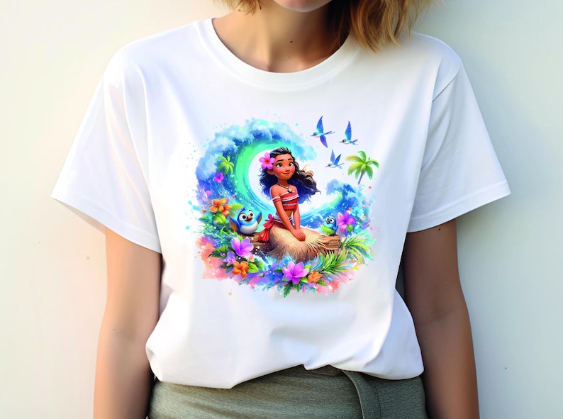 Peut inclure: T-shirt blanc avec un imprim&eacute; graphique color&eacute; de Moana du film Disney Moana. Le graphique repr&eacute;sente Moana assise sur un rocher avec une vague derri&egrave;re elle, entour&eacute;e de fleurs tropicales et d'oiseaux.