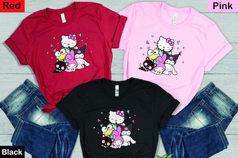 Pu&ograve; includere: Tre magliette con una stampa grafica di Hello Kitty e i suoi amici. Le magliette sono rossa, rosa e nera. La grafica presenta Hello Kitty, My Melody, Badtz-Maru e Keroppi.