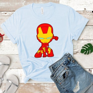 Puede incluir: Una camiseta azul claro con una imagen de dibujos animados de Iron Man con un traje rojo y amarillo. La imagen est&aacute; centrada en la camiseta.