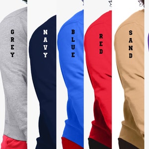 Puede incluir: Un conjunto de diez sudaderas de manga larga en varios colores, incluyendo blanco, negro, gris, azul marino, azul, rojo, arena, morado y rosa. Cada sudadera tiene una palabra vertical impresa en la manga, como "WHITE", "BLACK", "GREY", "NAVY", "BLUE", "RED", "SAND", "PURPLE", y "PINK".