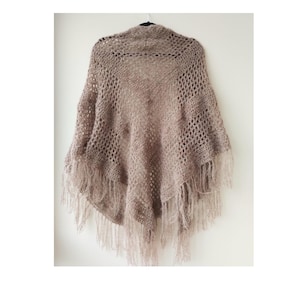 Könnte beinhalten: Ein braunes Häkeltuch mit Fransen. Das Tuch hat ein Spitzenmuster und ist aus weichem, flauschigem Garn gefertigt.