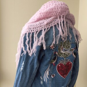 May include: A blue denim jacket with distressed details and embroidered birds and a heart with the text "Love Always, Love Often, Love Now" on the back. The jacket is worn with a pink crocheted scarf.