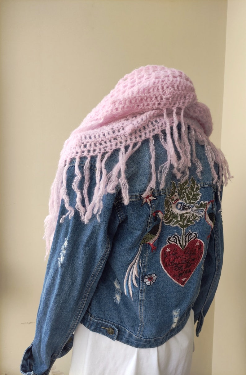 May include: A blue denim jacket with distressed details and embroidered birds and a heart with the text "Love Always, Love Often, Love Now" on the back. The jacket is worn with a pink crocheted scarf.