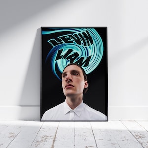 以下が含まれることがあります： 青と緑の渦巻き模様が描かれた白黒のポスター。デザインには黒色の「LEVIN LIAM」という文字が書かれている。短い茶色の髪をした男性がデザインを見上げている。彼は白い襟付きシャツを着ている。