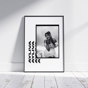 May include: Black and white photo print of a woman singing on stage. The photo is framed in a black frame and the woman's name "AYLIVA" is repeated in a bold, black font on the white background.
