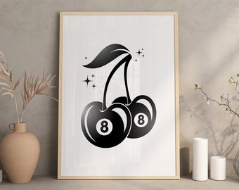 Op de afbeelding: Zwart-wit ingelijste kunstdruk met twee kersen, elk met een achtbalontwerp. De print bevat bladeren en steraccenten. Het kunstwerk wordt tentoongesteld op een plank met decoratieve vazen en kaarsen.
