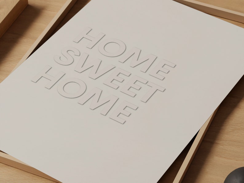 May include: A framed print with the text "Home Sweet Home" in a white, raised font on a beige background.