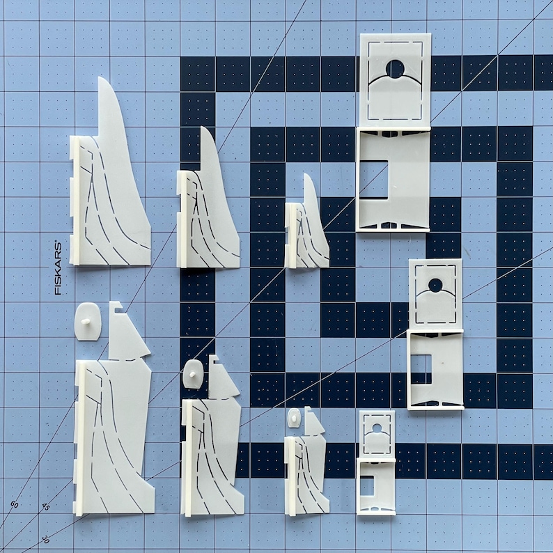 K&ouml;nnte beinhalten: Ein Satz wei&szlig;er Papierbastelteile zum Bau eines Modells. Die Teile sind ausgeschnitten und bereit zum Zusammenbauen. Die Teile sind mit dem Wort "FISKARS" beschriftet.