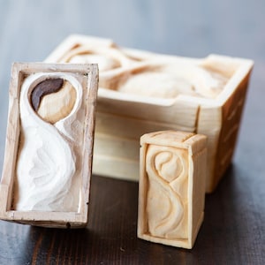 May include: A collection of hand-carved wooden art pieces. The set includes two rectangular frames with carved designs and a larger wooden box. The carvings feature abstract shapes and patterns, with a natural wood finish.